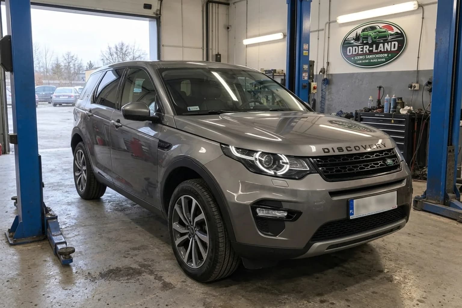 Wizualizacja AI: szary Land Rover Discovery Sport na podnośniku w warsztacie OderLand